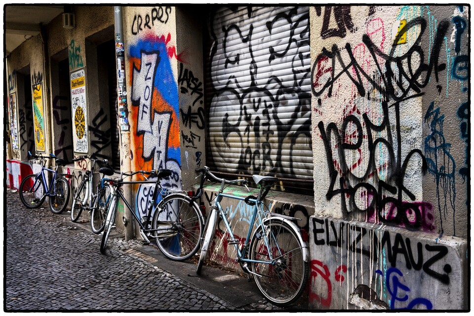 Cyklar lutade mot graffitiklädd fasad i bakgata