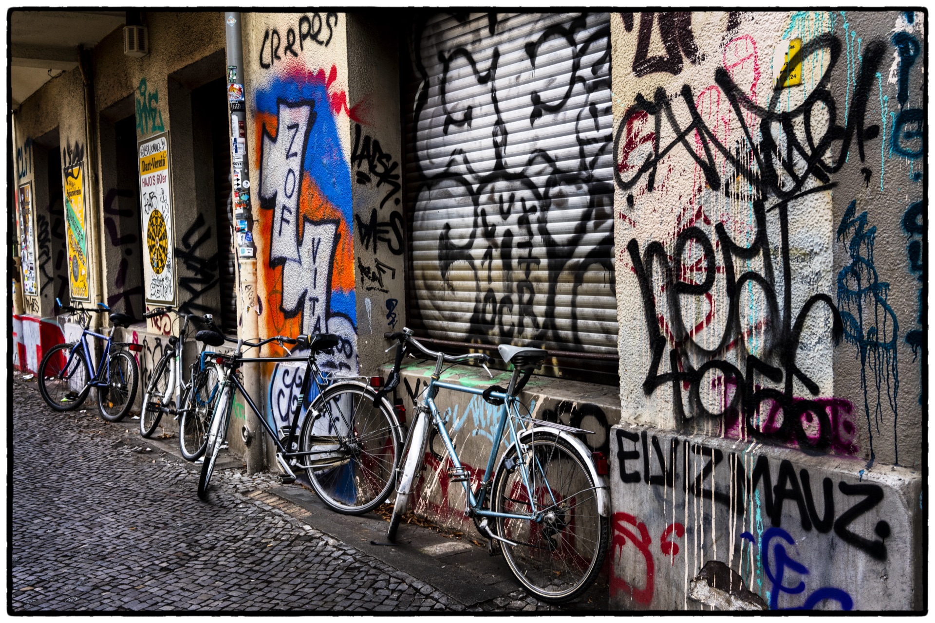 Cyklar lutade mot graffitiklädd fasad i bakgata