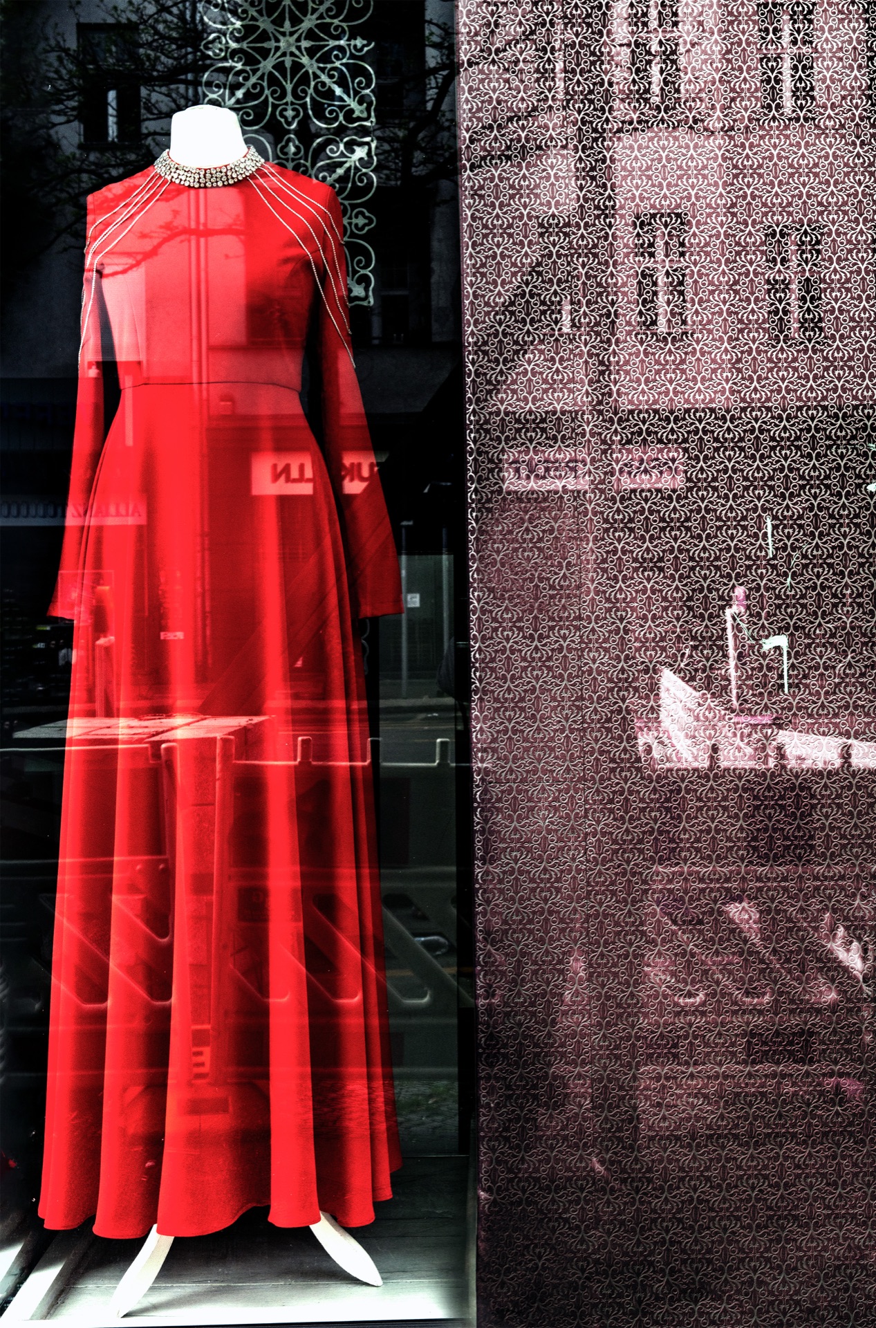 Röd aftonklänning på skyltdocka med stadsreflektioner i glaset