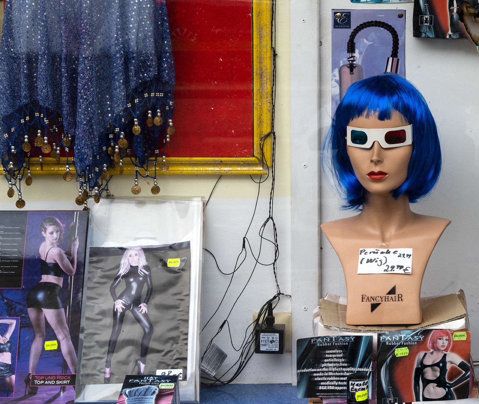 Skyltdocka med blå peruk och 3D-glasögon i kioskskyltfönster