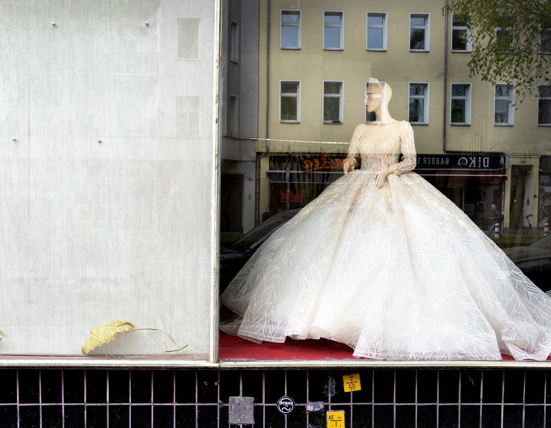 Brudklänning på skyltdocka med fasadreflektioner i skyltfönster