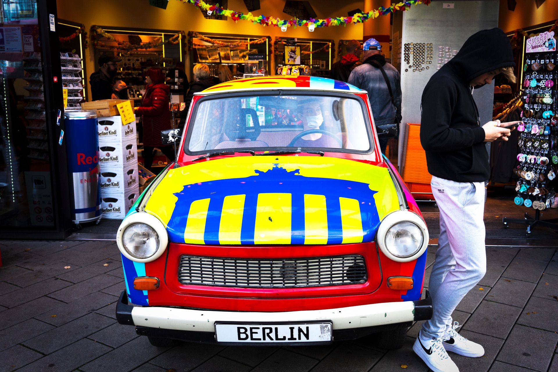 Färgglad Trabant med BERLIN-skylt framför souvenirbutik
