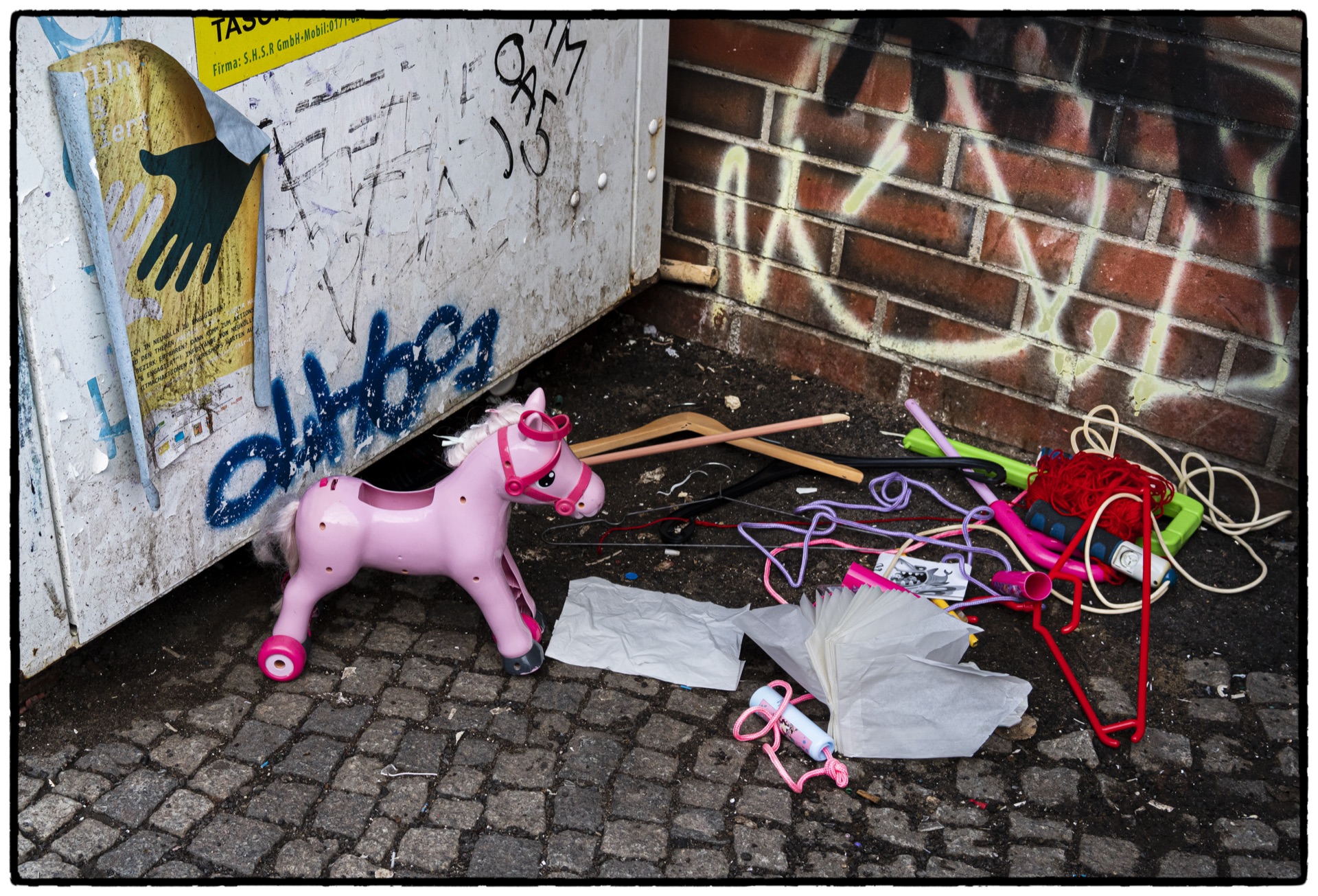 Rosa leksakshäst och färgglada föremål övergivna vid gatuhörn
