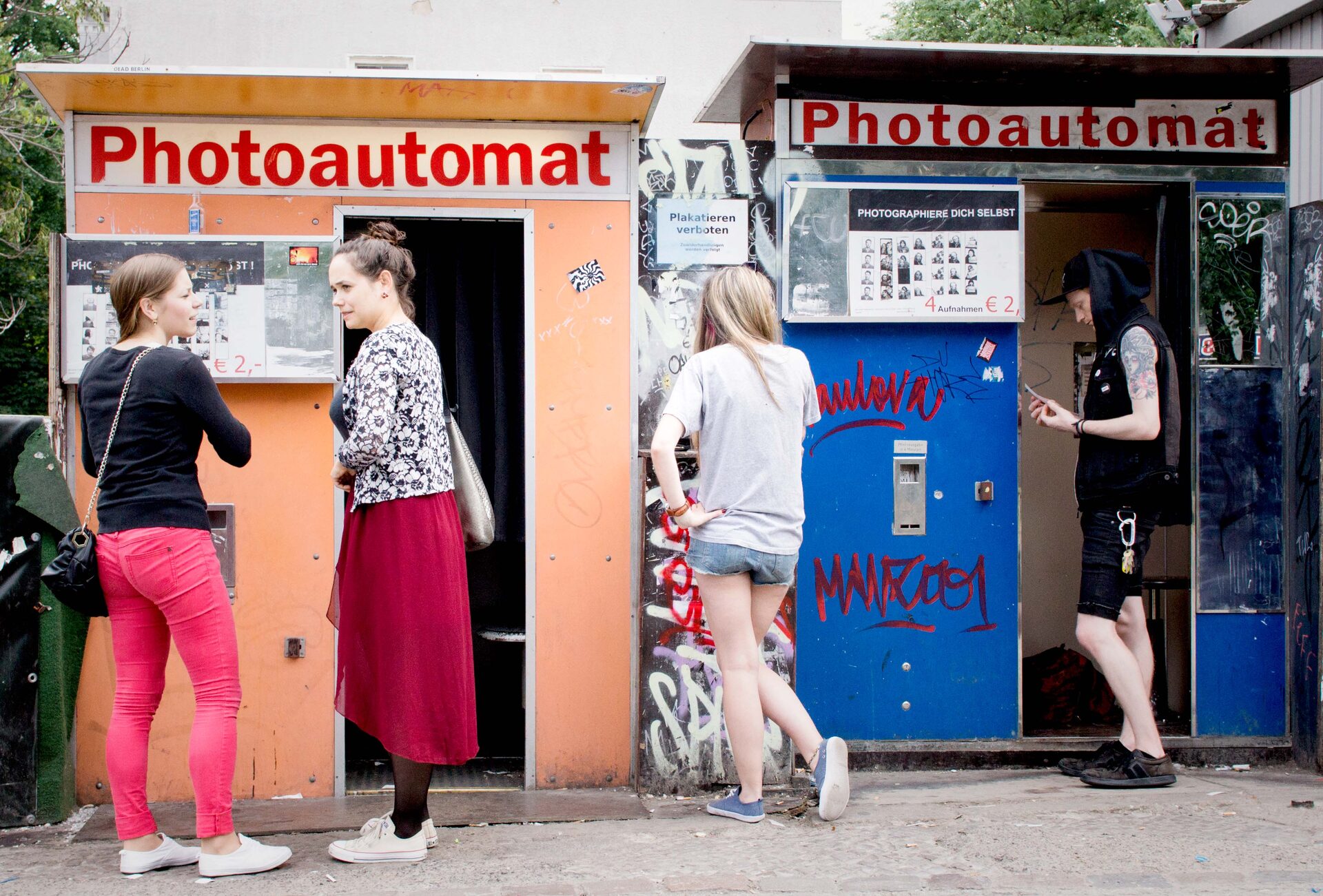 Unga kvinnor vid Photoautomat-bås på trottoar i Berlin
