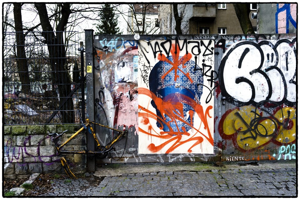 Färgstark graffitivägg med orange och blått bakom metallstaket