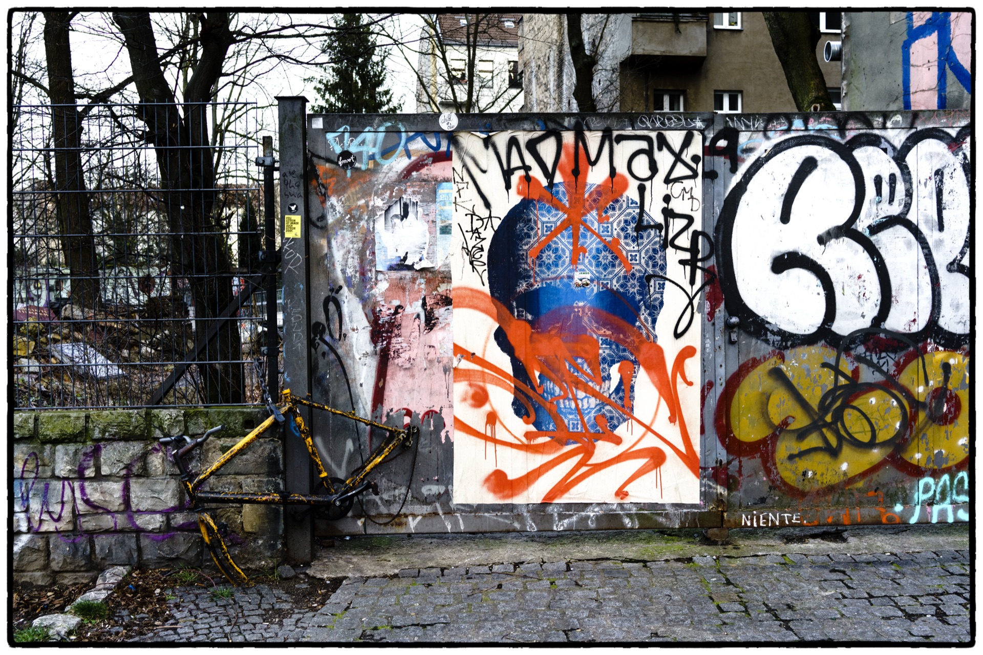 Färgstark graffitivägg med orange och blått bakom metallstaket