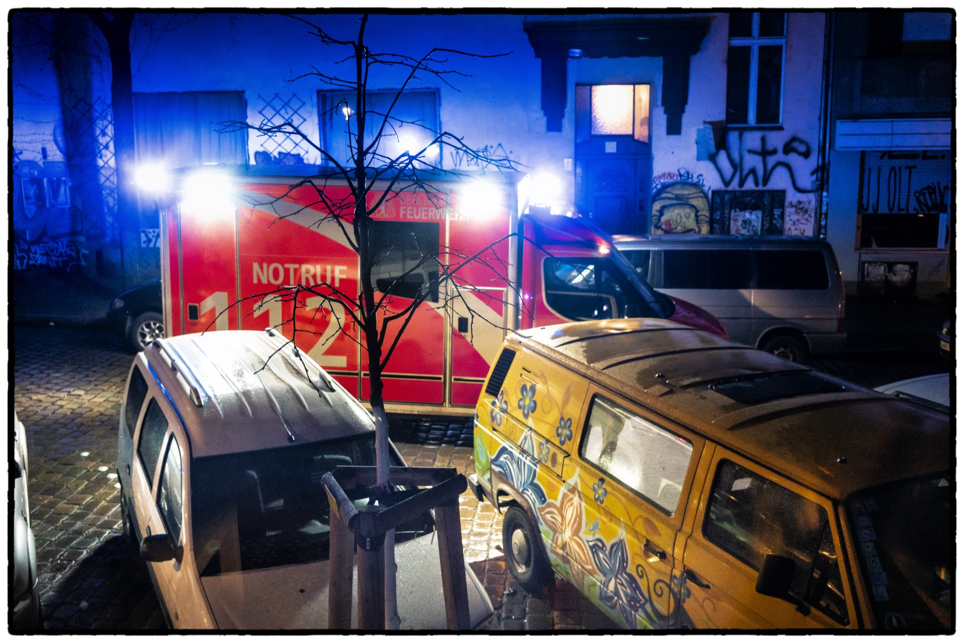 Brandbil och graffitimålad skåpbil i blått nattljus