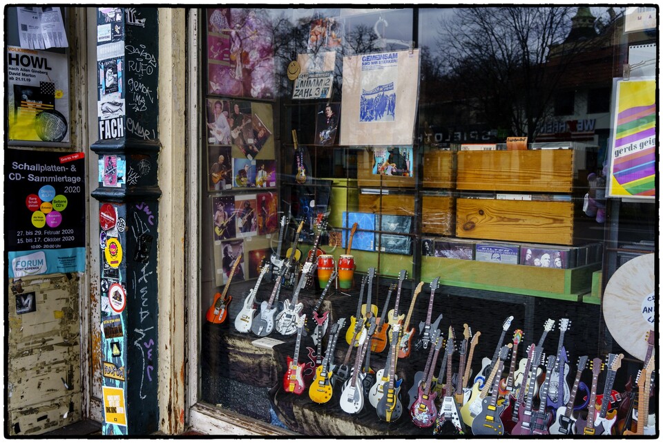 Skyltfönster med miniatyrgitarrer och skivor i sliten butik