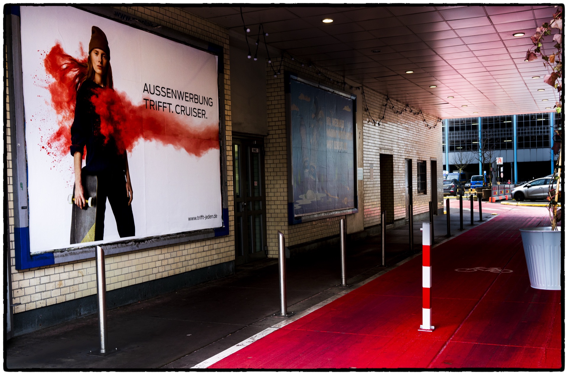 Reklamaffisch vid tunnelbaneingång med röd matta och pollare