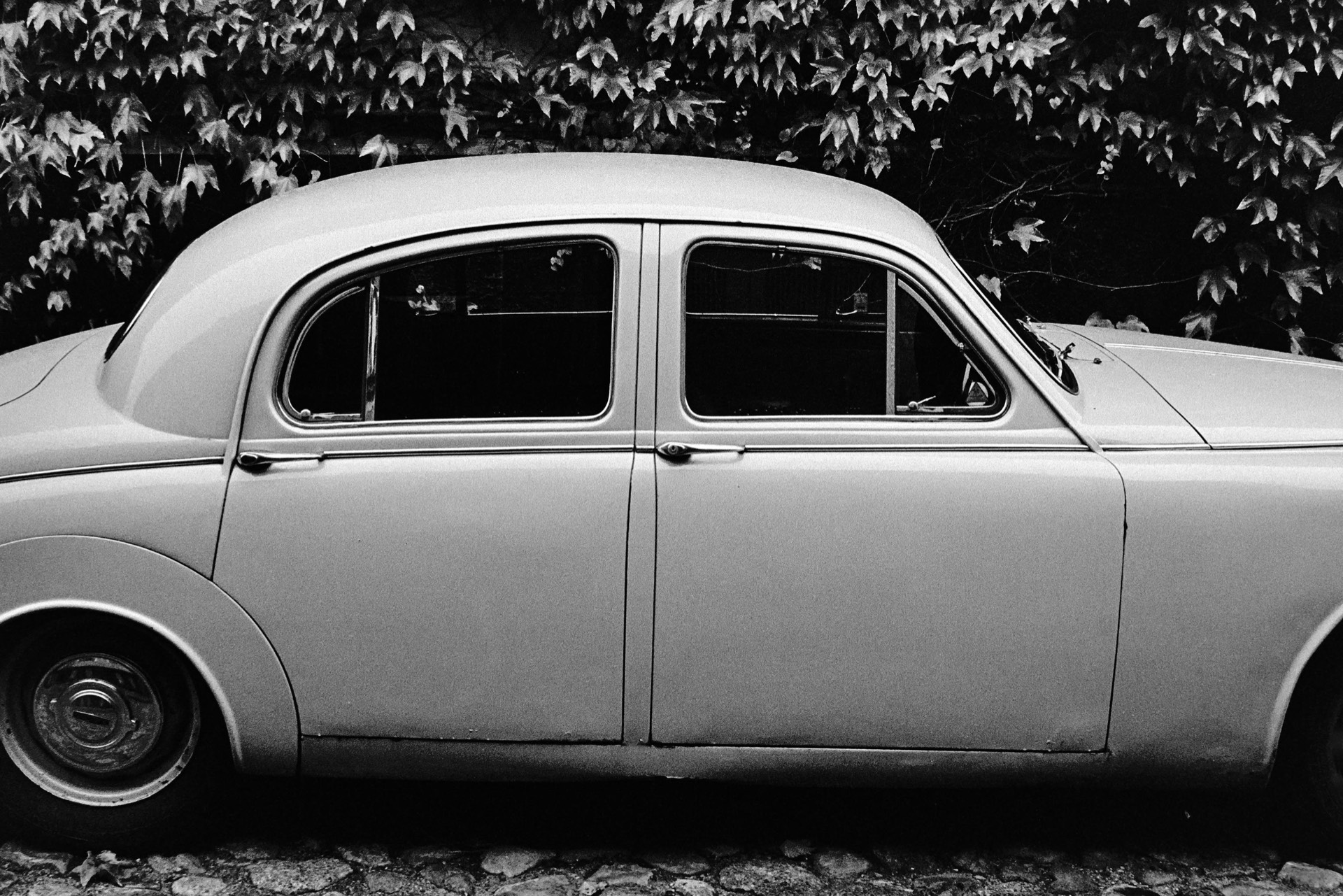 Klassisk rundad limousine parkerad framför murgröna