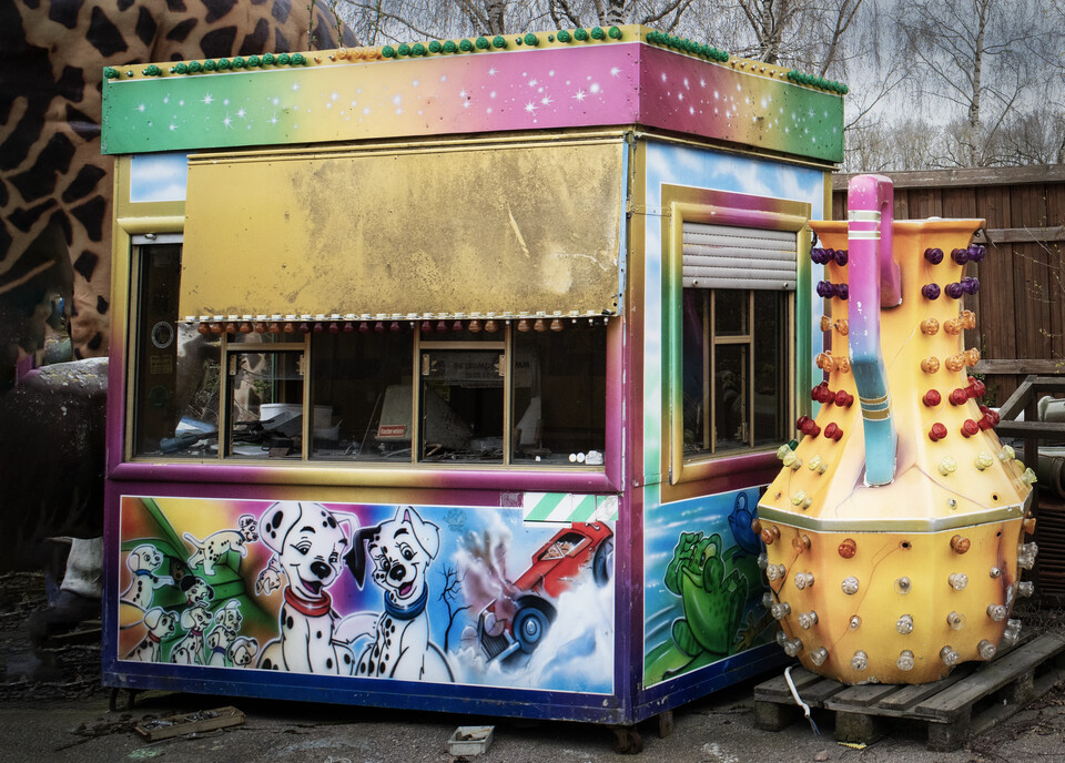 Övergiven tivolikiosk målad med dalmatiner och seriefigurer bredvid en gul nitprydd karusell