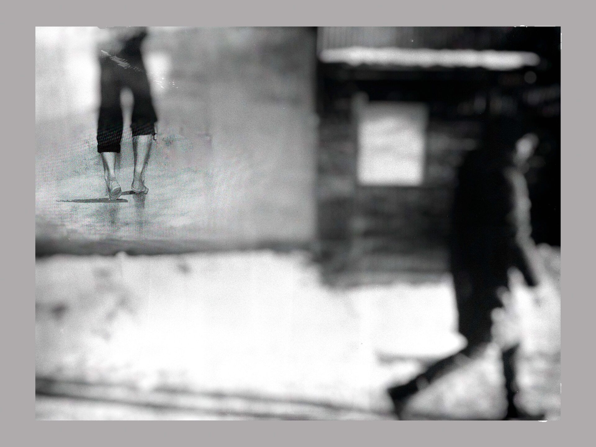 Drömlik dubbelexponering av figurer i stadslandskap, svartvitt