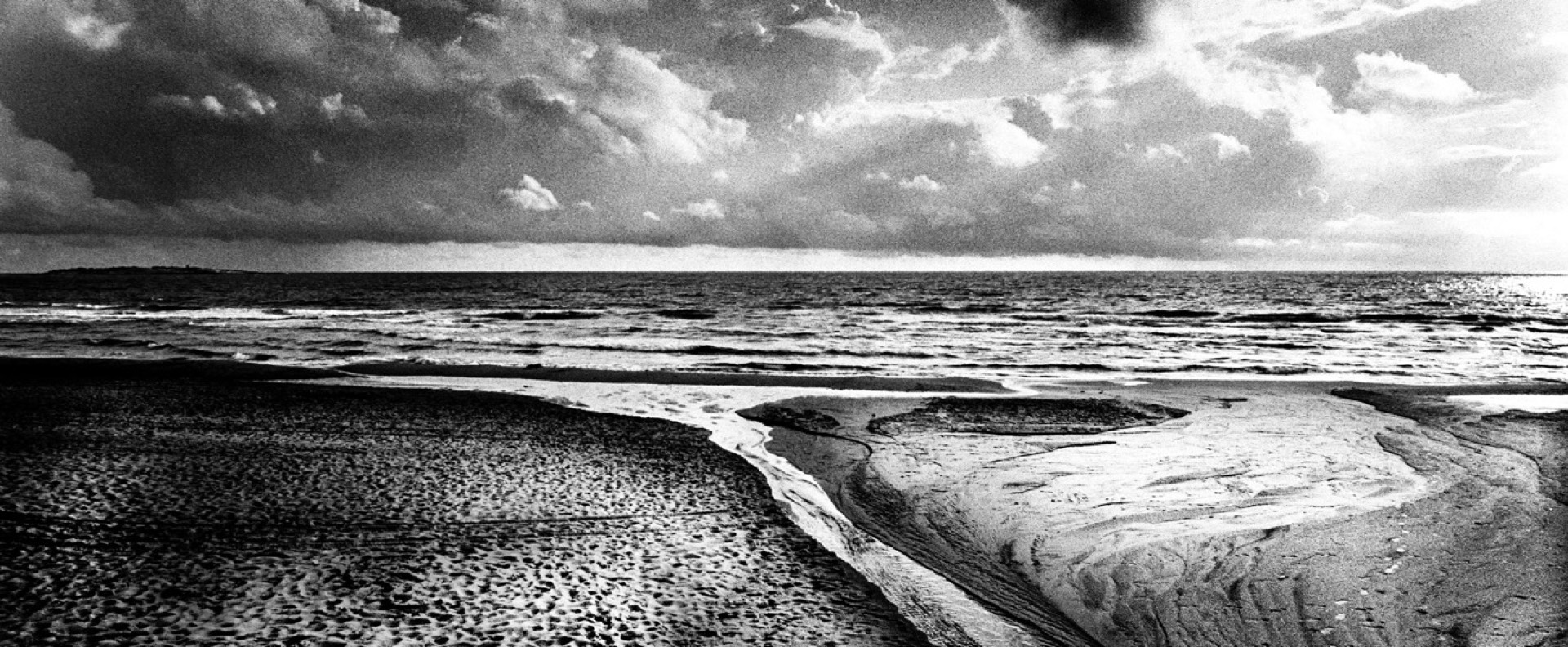 Dramatisk strand med vattenkanal och moln