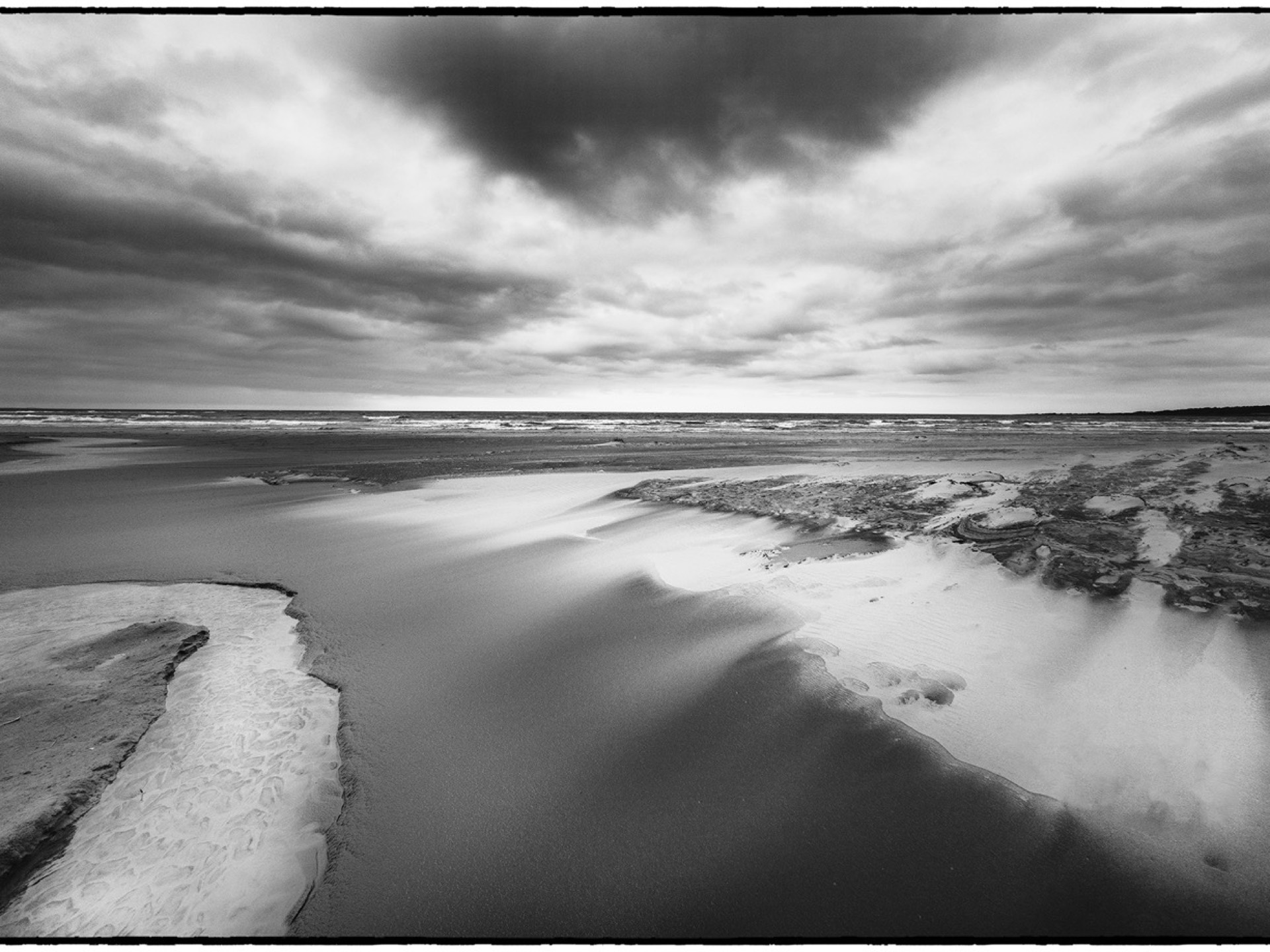 Dramatisk strand med moln och vattenkanaler