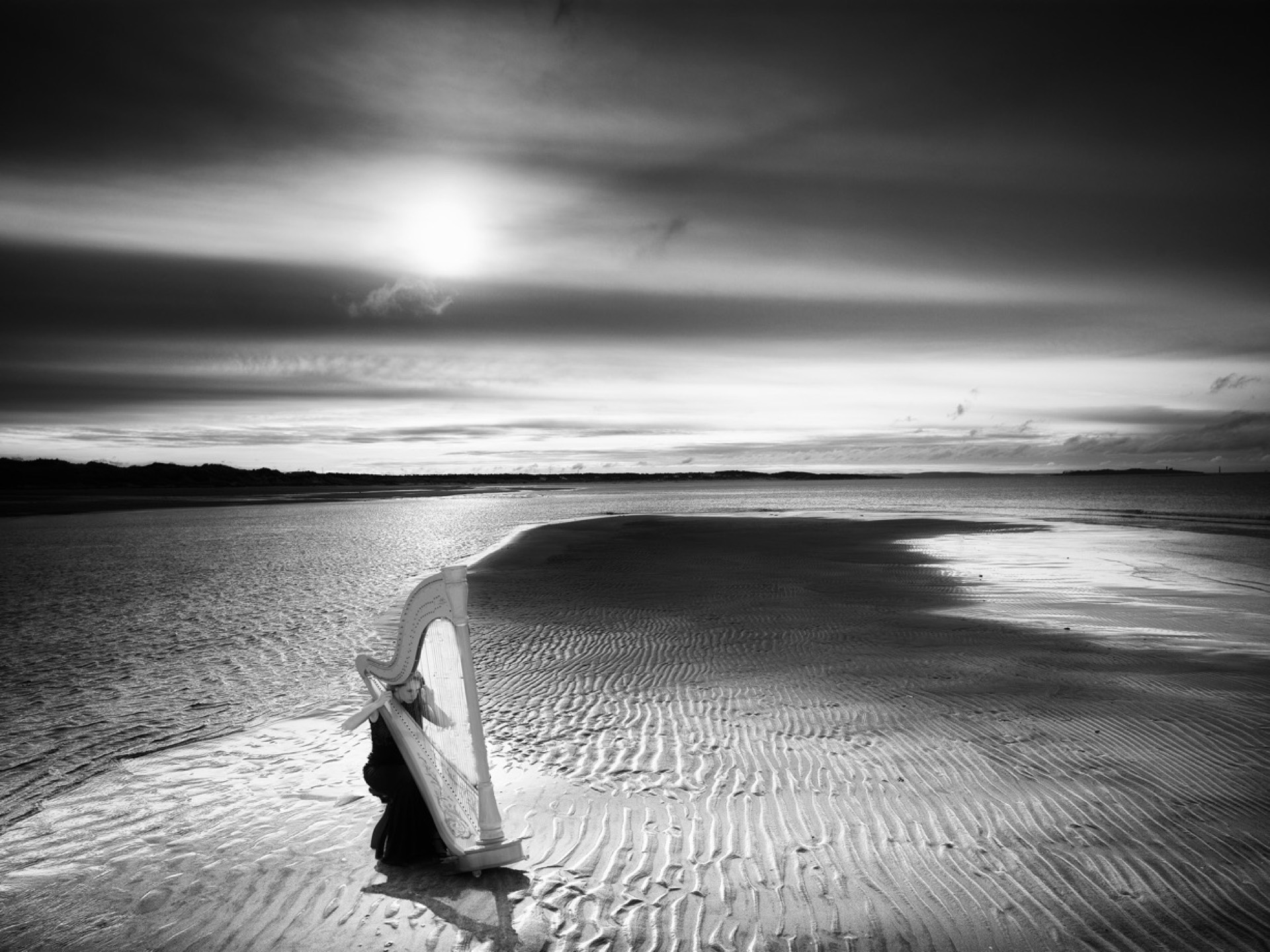 Harpist på strand vid solnedgång