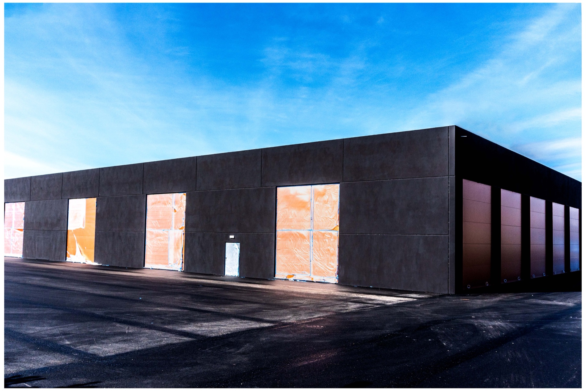 Mörk industribyggnad med igenspikade fönster mot blå himmel