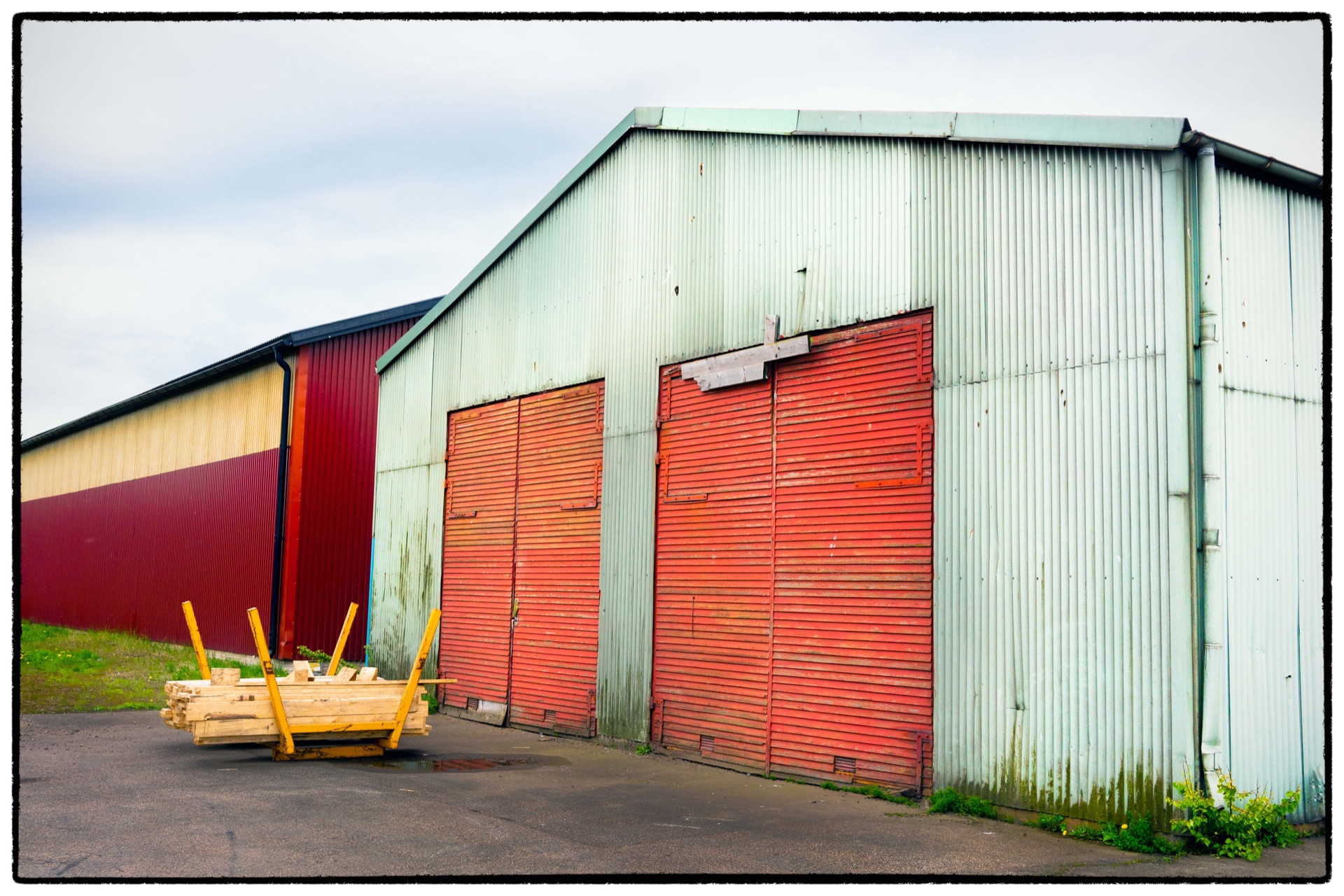 Plåtlagerbyggnader med röda skjutportar och en gul pallyftare
