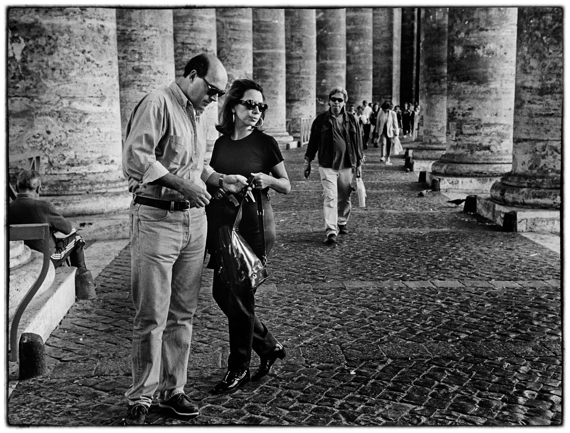 Par promenerar under kolonnaden vid Petersplatsen, svartvitt