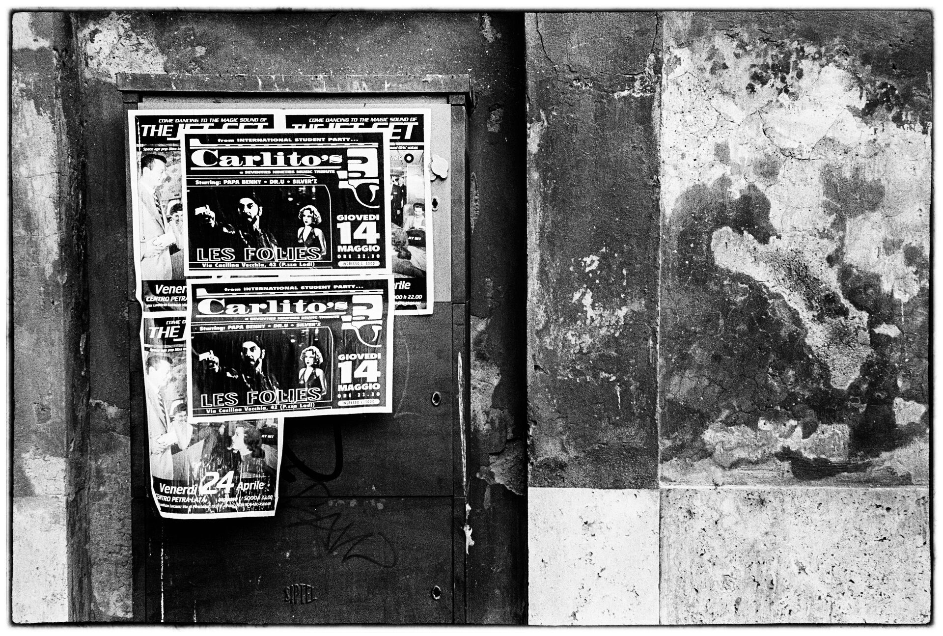 Affischer på vägg bredvid flagnad putsyta och marmorblock