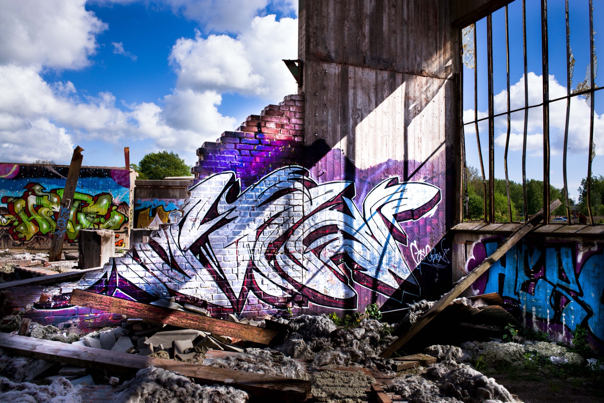 Stor lila och vit graffiti på tegelvägg i rivningstomt