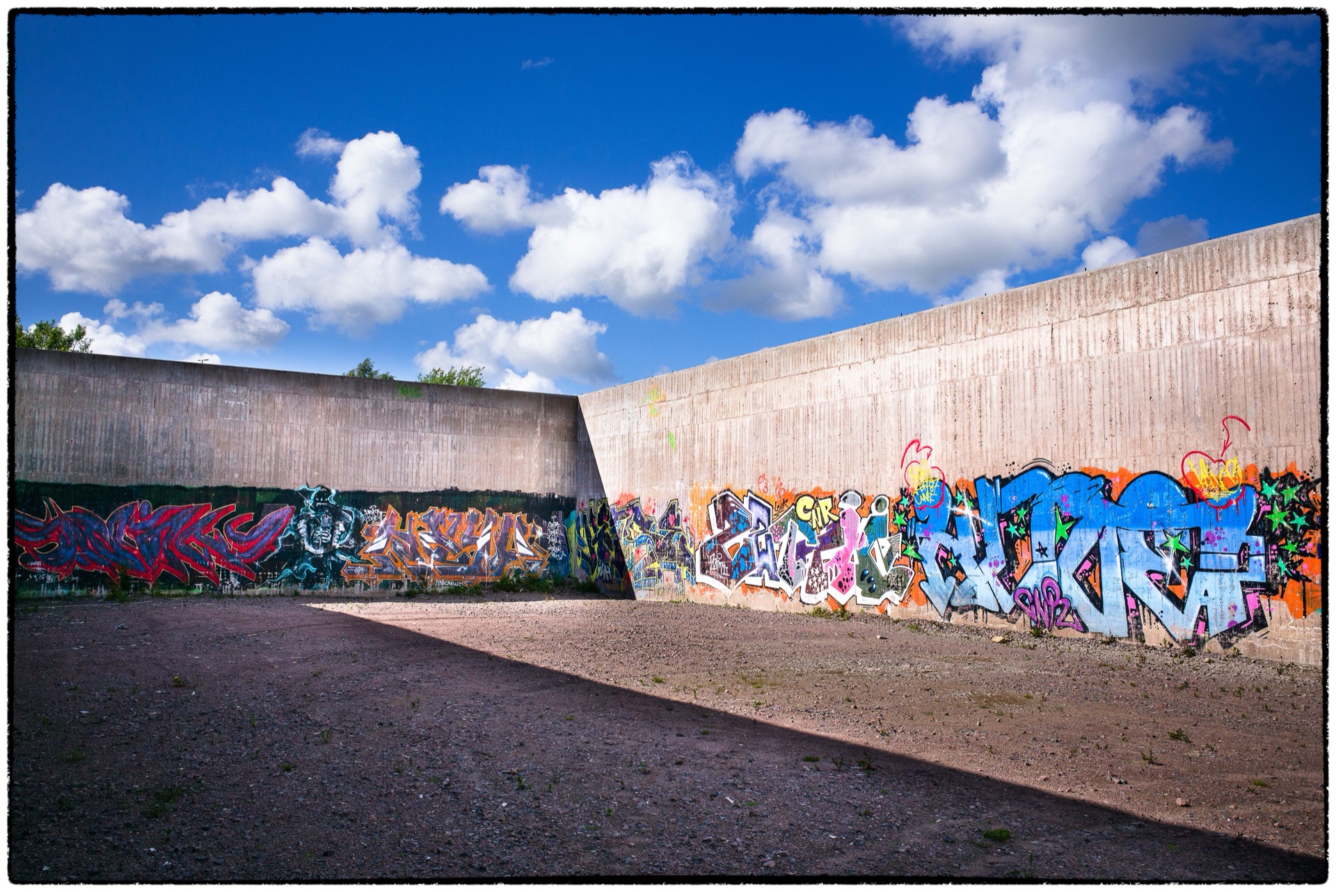 Graffitiklädda betongmurar bildar gång under öppen himmel
